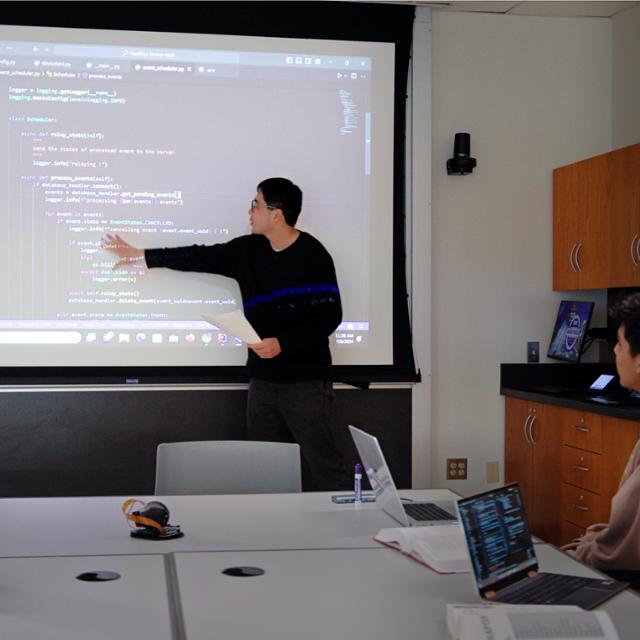 students and professor looking at a computer