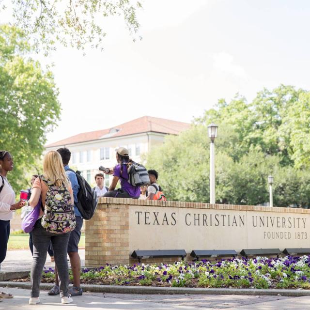 Students hang out by one of the TCU signs on campus
